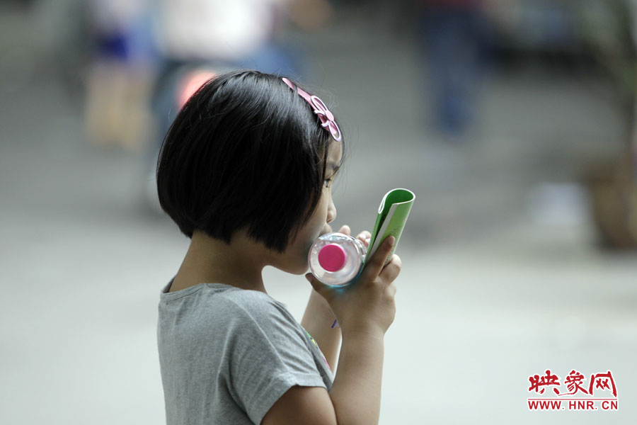 6月7日，鄭州回中考點，一名孩子拿著一瓶礦泉水，等待哥哥走出考場