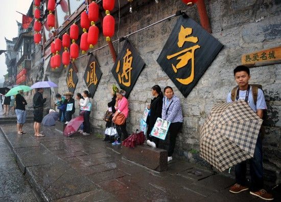 　4月29日上午11時(shí)20分，一些游客和古城當(dāng)?shù)氐木用穸阍谝粋€(gè)酒吧的屋檐下避雨。這些當(dāng)?shù)鼐用褚詾橛慰团恼罩\生，一場(chǎng)降雨讓他們的生意更加清淡。