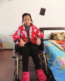 陳慶霞坐在輪椅上。她現在下身癱瘓，疾病纏身，生活不能自理。