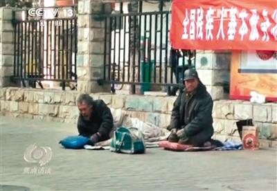 工人體育場北路，兩位乞討者路邊乞討，并輪流扮成“病人”（躺地者）。 央視截圖