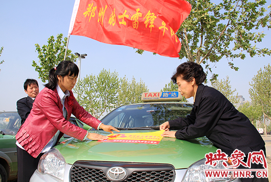 　　授旗結(jié)束后，首都的士雷鋒車(chē)隊(duì)王鳳進(jìn)隊(duì)長(zhǎng)（右）與鄭州的的哥的姐在車(chē)身上貼上標(biāo)識(shí)。