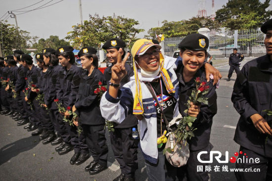 2013年12月03日,曼谷總理府與曼谷警署允許反政府示威民眾進入,雙方進入暫時“停戰(zhàn)”狀態(tài)迎接泰王生日。曼谷警察總署,女警們手持鮮花送給反政府示威民眾。圖片來源:Manish Swarup/東方IC