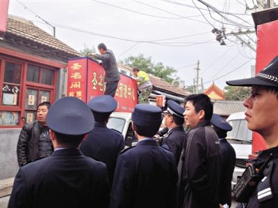 昨日下午,東城區工商、城管、公安等部門,對雍和宮附近的預測中心進行清理整頓,站在車頂的兩名工人正拆除一家“預測中心”的招牌。因雍和宮、白云觀等文化景點外聚集大量算命先生,被媒體稱為“算命一條街”。本版攝影/新京報記者 李寧 攝