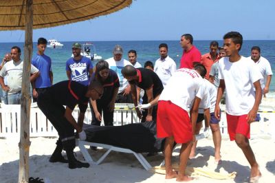 6月26日，在突尼斯蘇塞，救生員和醫務人員在發生襲擊事件的海灘運送一名死者的遺體。新華社發