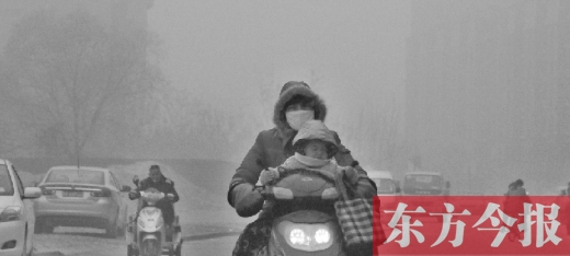 12月8日，鄭州市未來(lái)路上，一位市民帶著孩子在霧中騎行