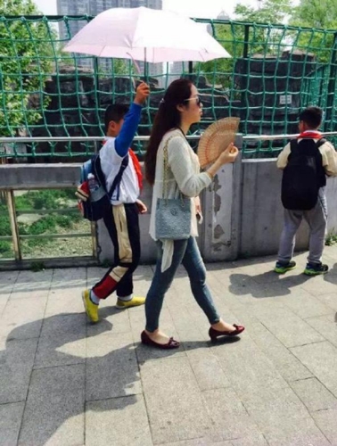 小學生為女教師打陽傘 小學生為女教師打陽傘